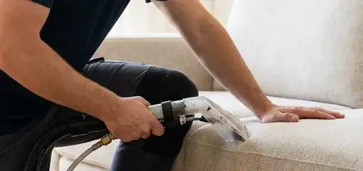 Professional upholstery cleaner deep-cleaning a fabric sofa with a handheld extraction tool, Miami, FL.